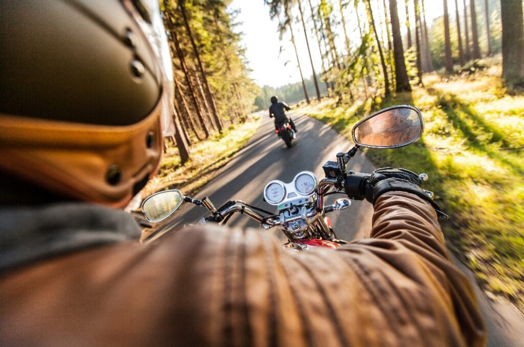 Man seat on the motorcycle on the forest road.